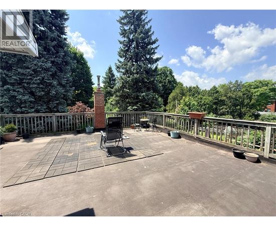 A patio with a chair and table is surrounded by a fence and trees.