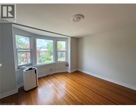 A room with wooden floors and a window overlooking a residential area.