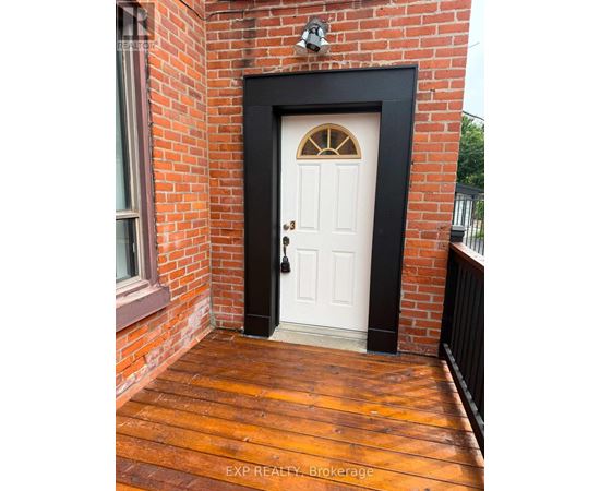 A white door with a black frame is set in a brick wall.
