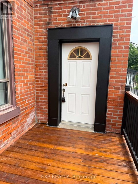 A white door with a black frame is set in a brick wall.