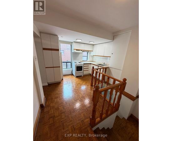 A kitchen with white cabinets and a wooden staircase.