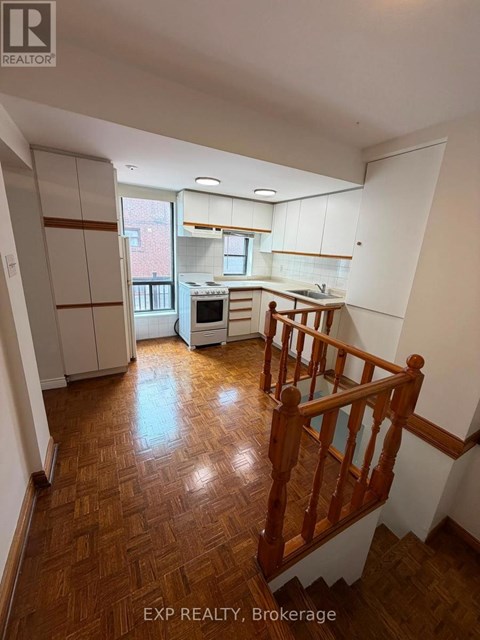 A kitchen with white cabinets and a wooden staircase.