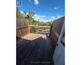 A wooden deck with a view of the sky and trees.