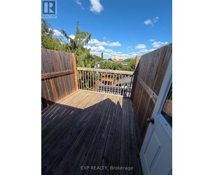 A wooden deck with a view of the sky and trees.