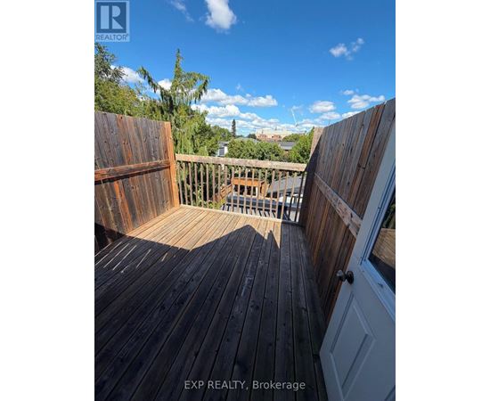 A wooden deck with a view of the sky and trees.