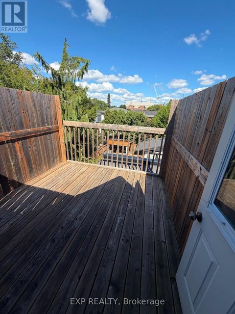 A wooden deck with a view of the sky and trees.
