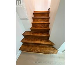 A set of wooden stairs with a white wall on the side.