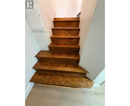 A set of wooden stairs with a white wall on the side.