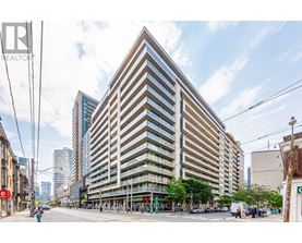 A tall building with a beige facade stands in the middle of a city street.