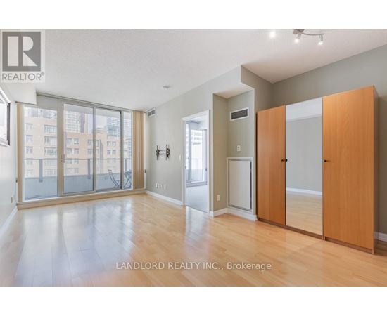 A spacious room with wooden floors and a large window overlooking a cityscape.