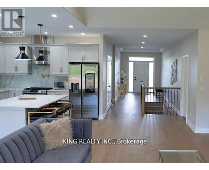 A modern kitchen with a dining table and a grey couch.