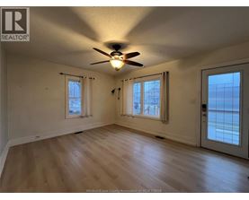 A room with a ceiling fan and two windows.