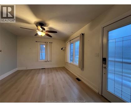 A room with a ceiling fan and wooden flooring.