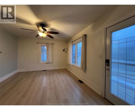 A room with a ceiling fan and wooden flooring.