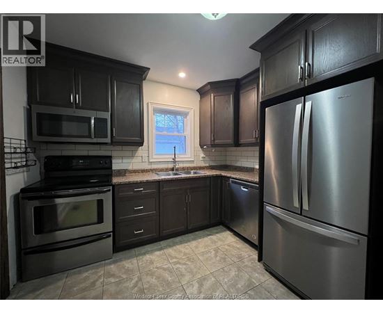 A kitchen with black cabinets and stainless steel appliances.