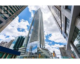 A tall building with a glass facade stands in the middle of a cityscape.