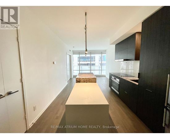 A spacious kitchen with black cabinets and a white island.