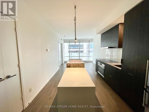 A spacious kitchen with black cabinets and a white island.