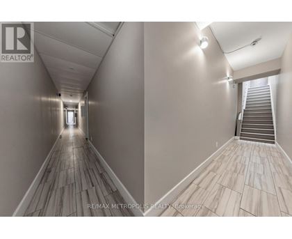 A hallway with wooden floors and a staircase on the right side.