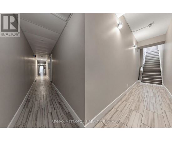 A hallway with wooden floors and a staircase on the right side.