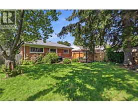 A house with a green lawn and trees in front.