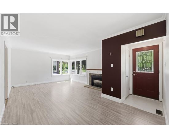A spacious room with a fireplace and a door leading to another room.
