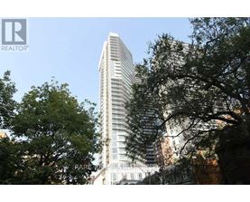 A tall building with many windows is surrounded by trees.