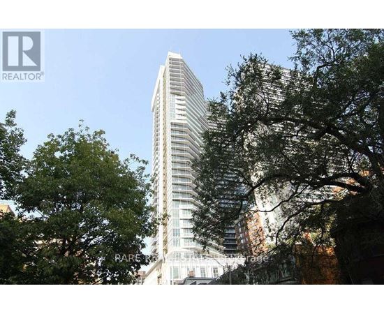 A tall building with many windows is surrounded by trees.