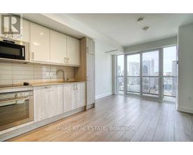 A spacious kitchen with wooden floors and a large window overlooking the city.