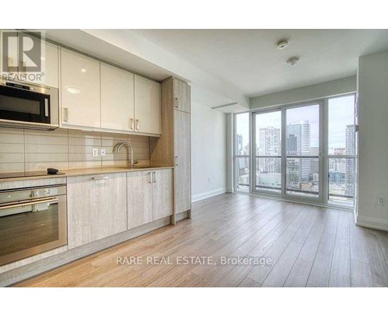 A spacious kitchen with wooden floors and a large window overlooking the city.