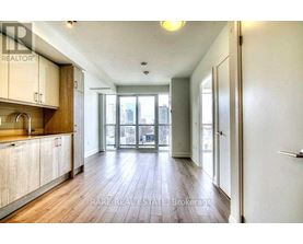 A spacious room with wooden floors and a large window overlooking a cityscape.