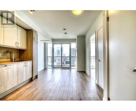 A spacious room with wooden floors and a large window overlooking a cityscape.
