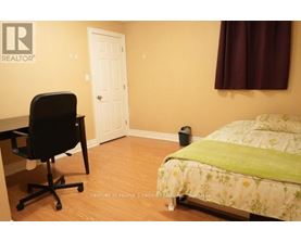 A bedroom with a bed, desk, and chair.