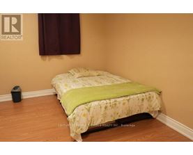 A bed with a green blanket in a room with a brown wall.