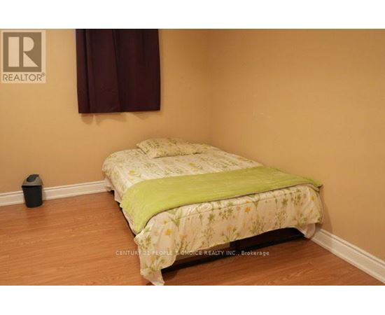 A bed with a green blanket in a room with a brown wall.