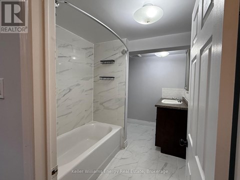 A bathroom with a marble tiled shower and a white bathtub.