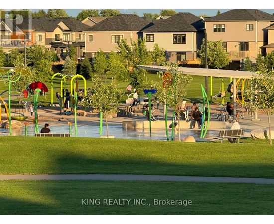 A playground with swings and a slide in a park with houses in the background.