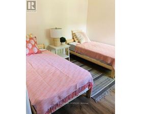A bedroom with two beds and a nightstand with a lamp.