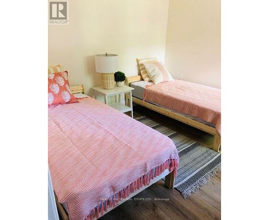 A bedroom with two beds and a nightstand with a lamp.