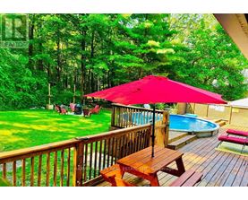 A red umbrella is on a wooden deck overlooking a pool.