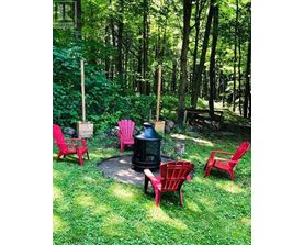 A fire pit surrounded by red chairs in a grassy area.