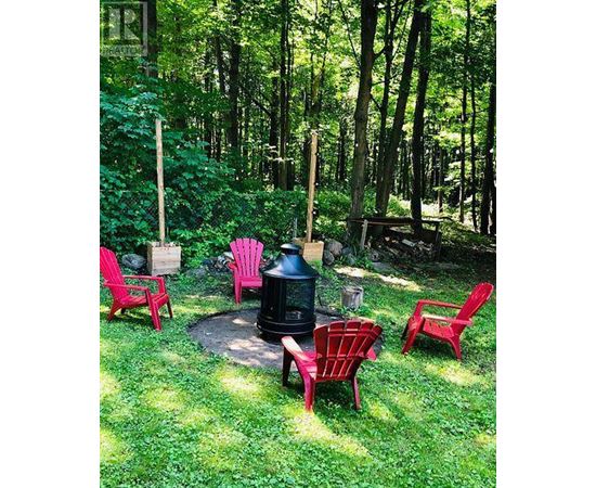 A fire pit surrounded by red chairs in a grassy area.