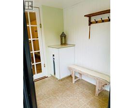 A wooden bench sits in a room with white walls.
