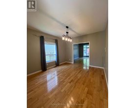 A spacious room with wooden flooring and a large window with curtains.