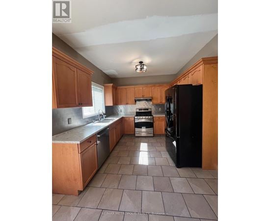 A kitchen with wooden cabinets and a black refrigerator.