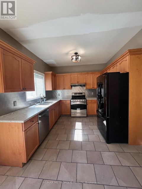 A kitchen with wooden cabinets and a black refrigerator.