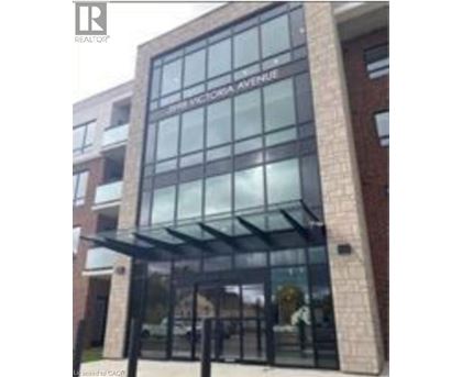 The entrance to a building with a glass facade and a brick wall.
