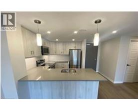 A modern kitchen with a stainless steel island and pendant lights.