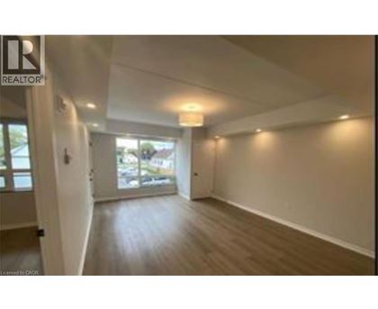 A spacious room with wooden flooring and white walls.