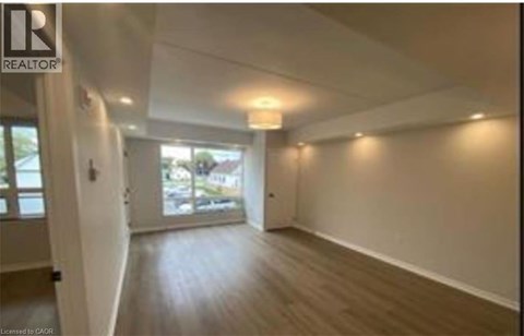 A spacious room with wooden flooring and white walls.